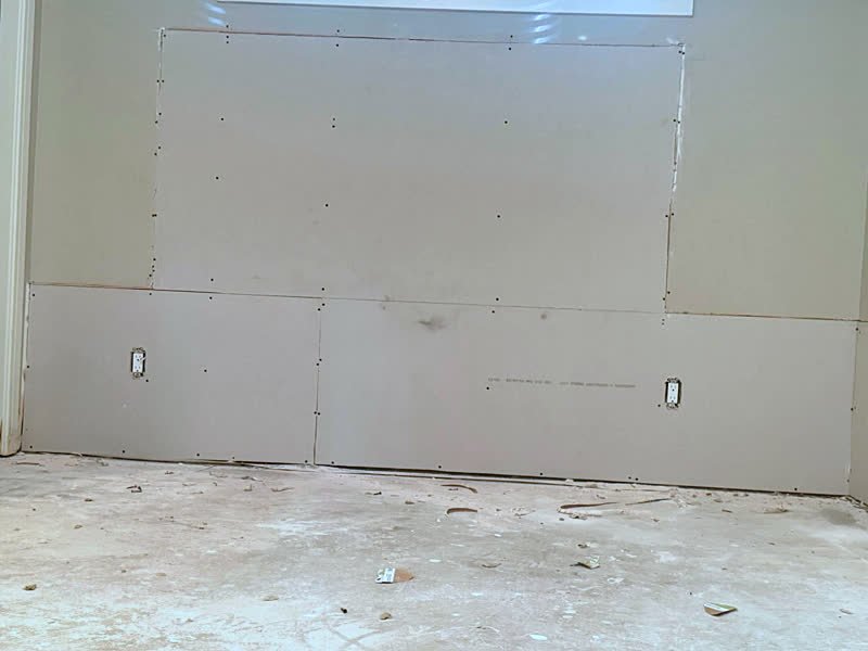 New drywall panels fastened to the lower wall