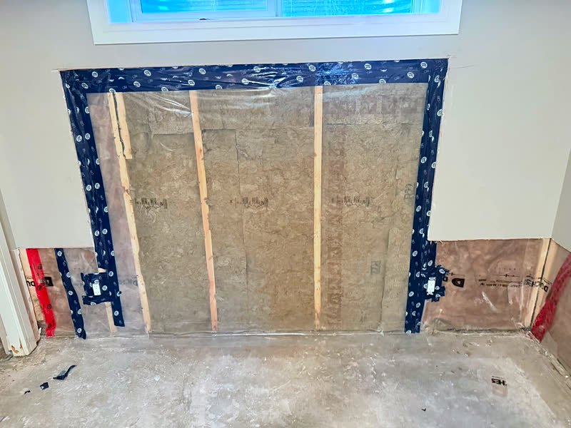 Wall section with new insulation and poly vapour barrier sealed with tape around outlets